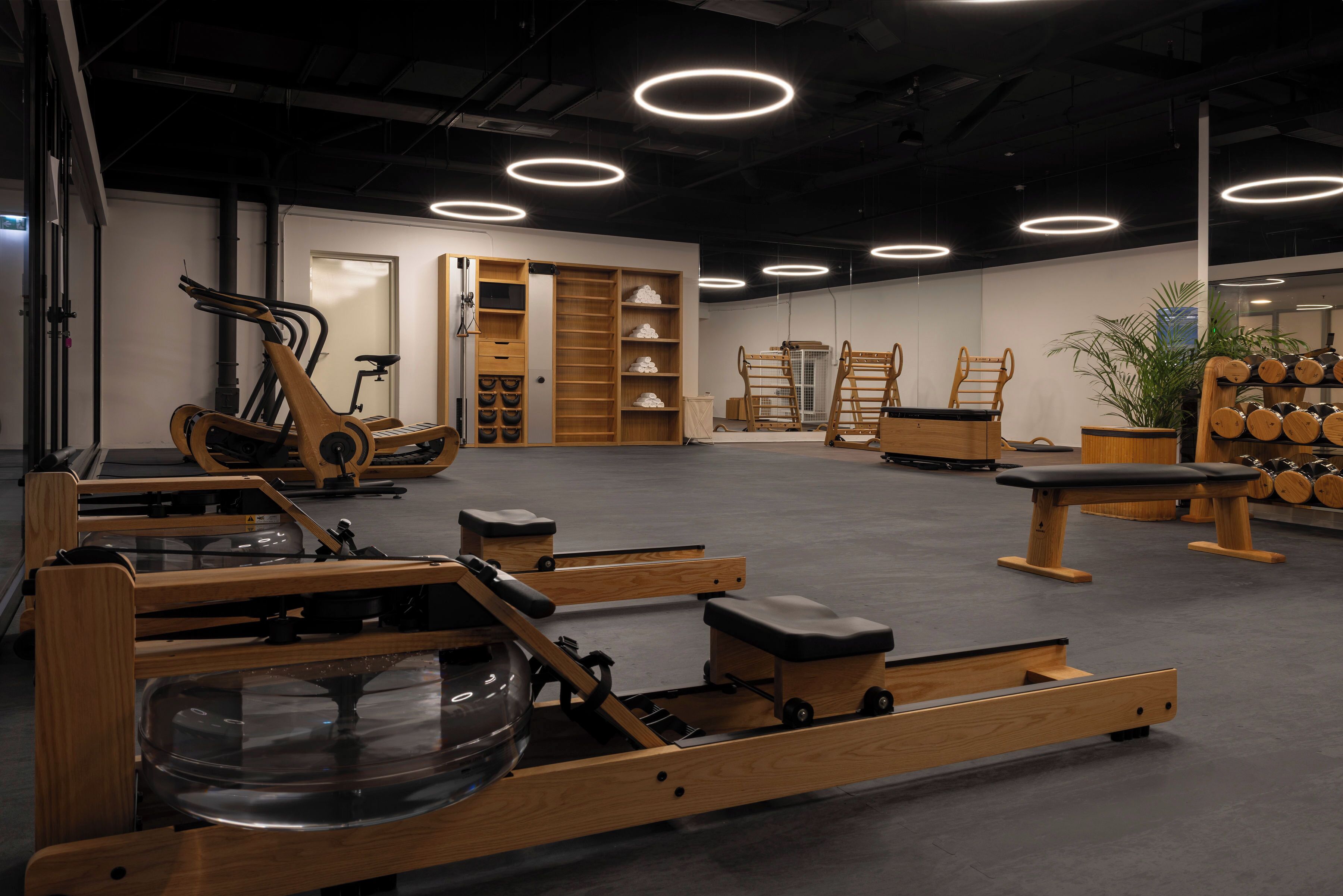 Een sportschool met trainingsapparatuur, houten meubels en een grote spiegel.