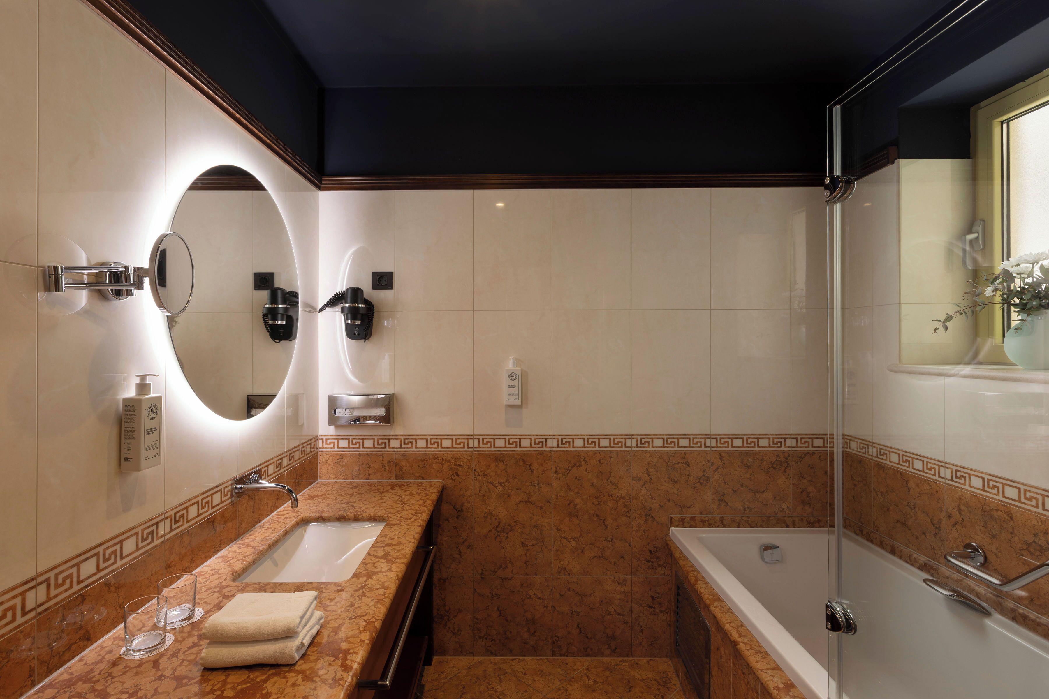 Un baño moderno con tocador de mármol, un espejo grande, una bañera y una zona de ducha.