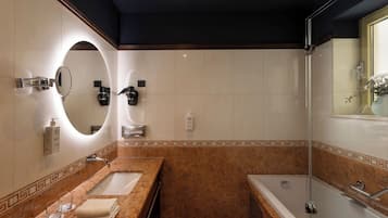 Un baño moderno con tocador de mármol, un espejo grande, una bañera y una zona de ducha.