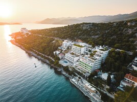 Un hotel sulla costa con diversi edifici, una piscina e un molo.