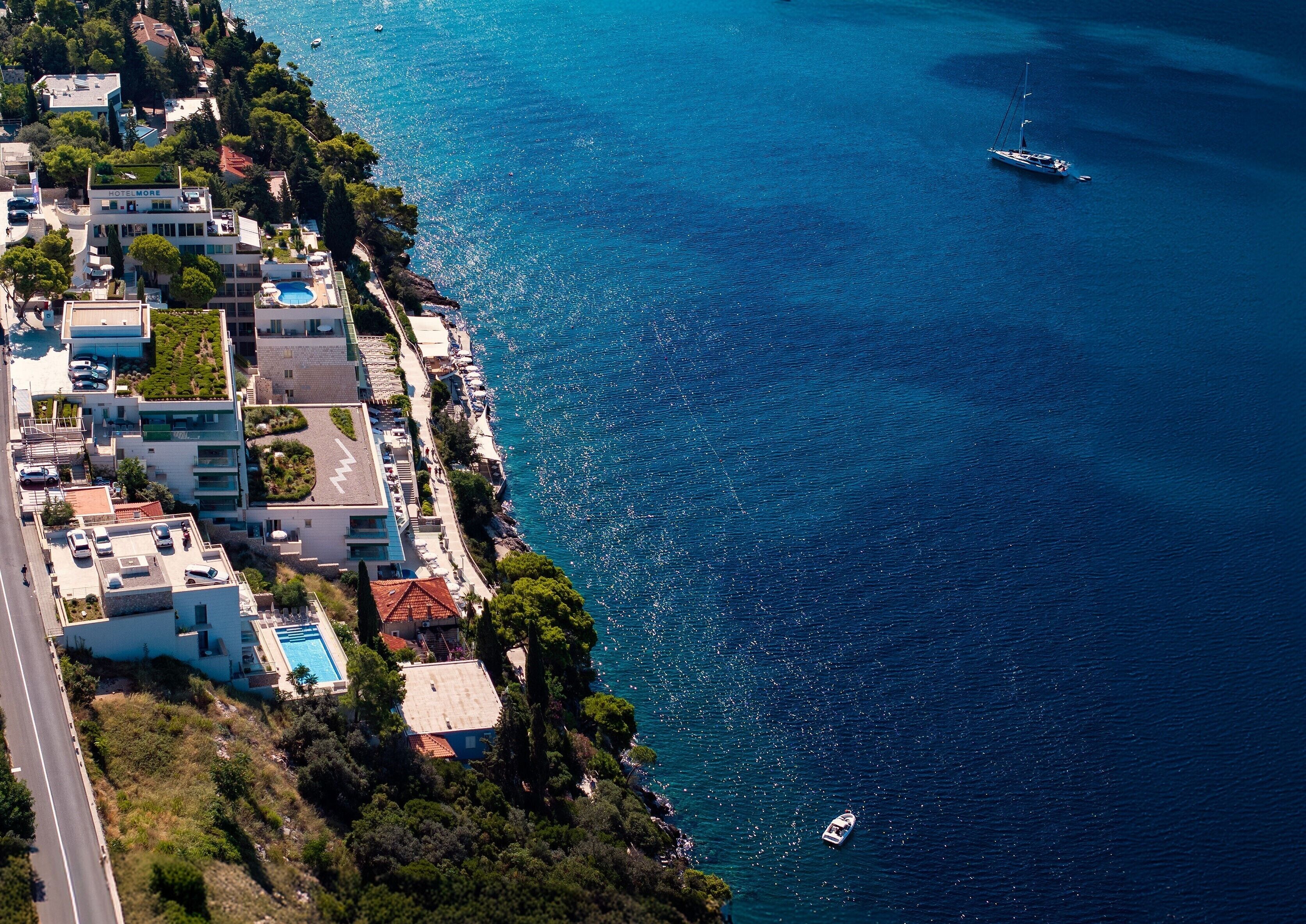 A coastal hotel with a swimming pool, a marina, and a road adjacent to the property.