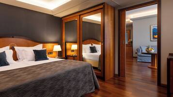 Quarto de hotel com uma cama grande, um guarda-roupa, uma escrivaninha com luminária e um quadro na parede.