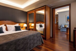 Een hotelkamer met een groot bed, een kledingkast, een bureau met lamp en een schilderij aan de muur.