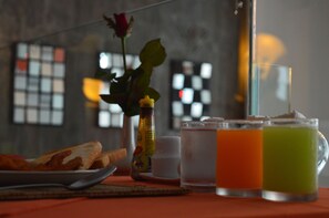 A breakfast setting with toast, a rose, a bottle, and two glasses of juice on a table. - Aya Boutique Hotel Pattaya (Pattaya)