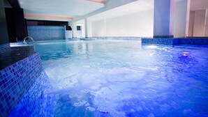 Una amplia piscina interior con agua cristalina azul, paredes de azulejos y diseño moderno.