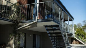 A multi-story building with a balcony, stairs, and a brick wall. - Aotea Motel (Christchurch)