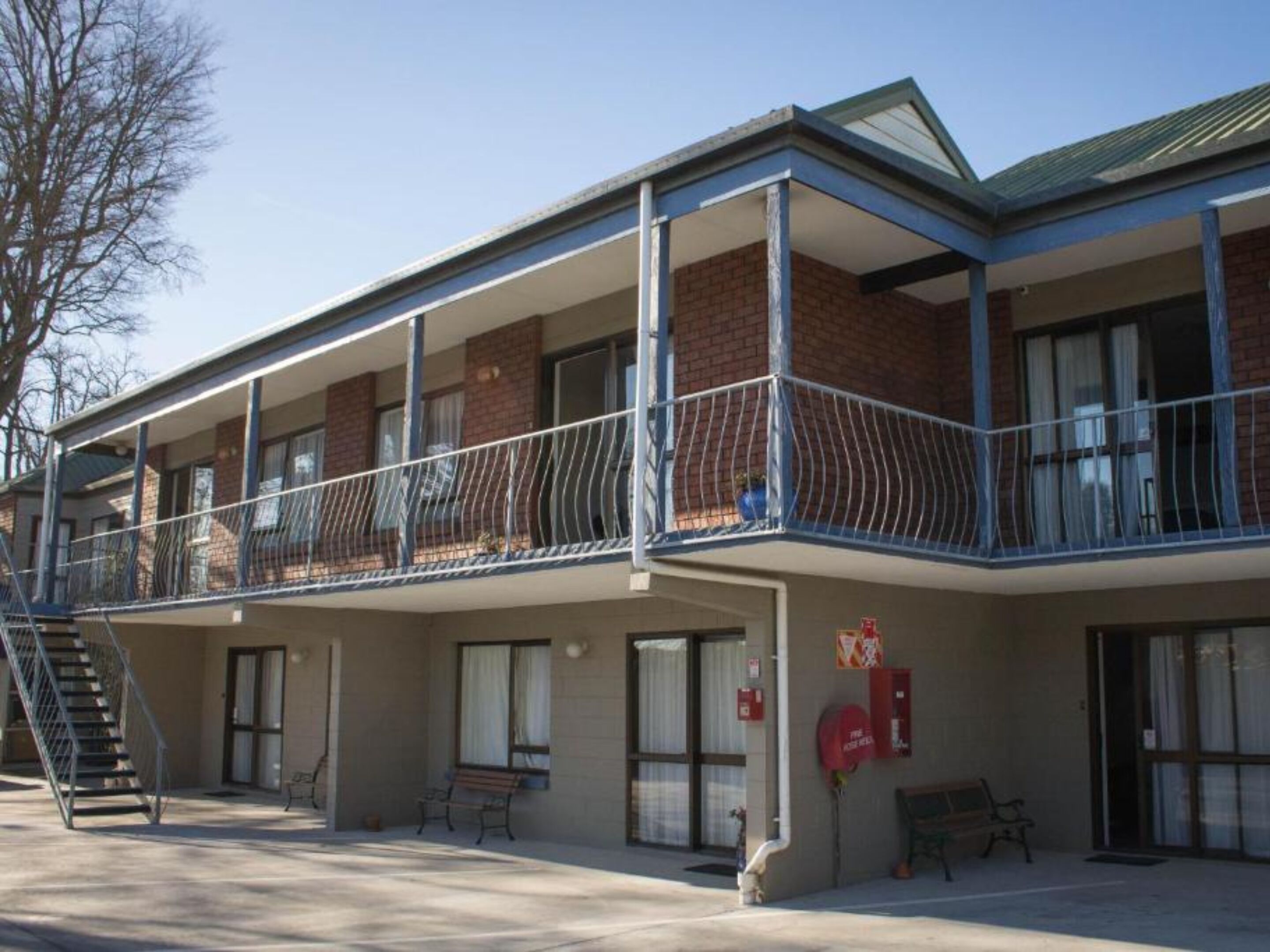 Un immeuble à plusieurs étages, doté d’un toit plat, d’un balcon couvert et d’une lance d’incendie fixée au mur.