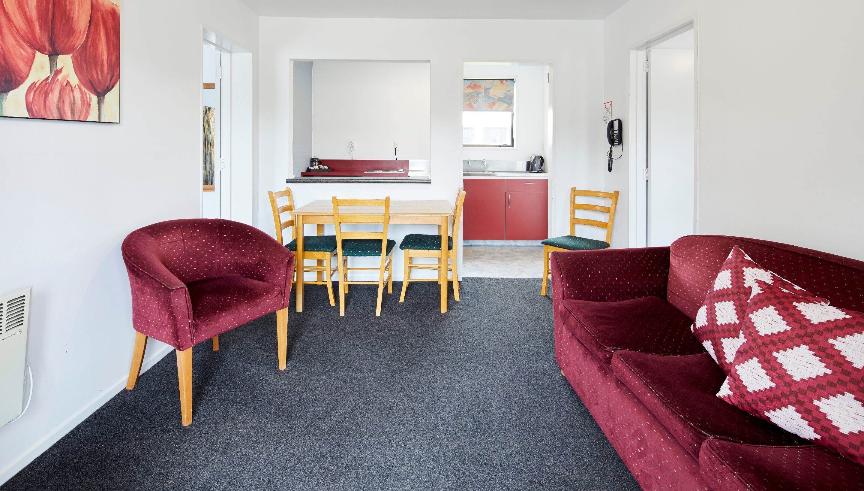 A compact living space with a dining area, a kitchenette, and a sofa with patterned cushions.