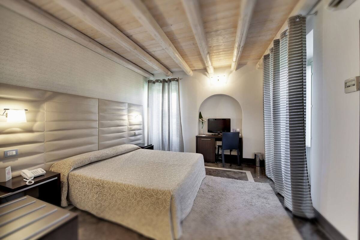 Une chambre d’hôtel avec un grand lit, un bureau avec un ordinateur, un téléphone et une télévision.