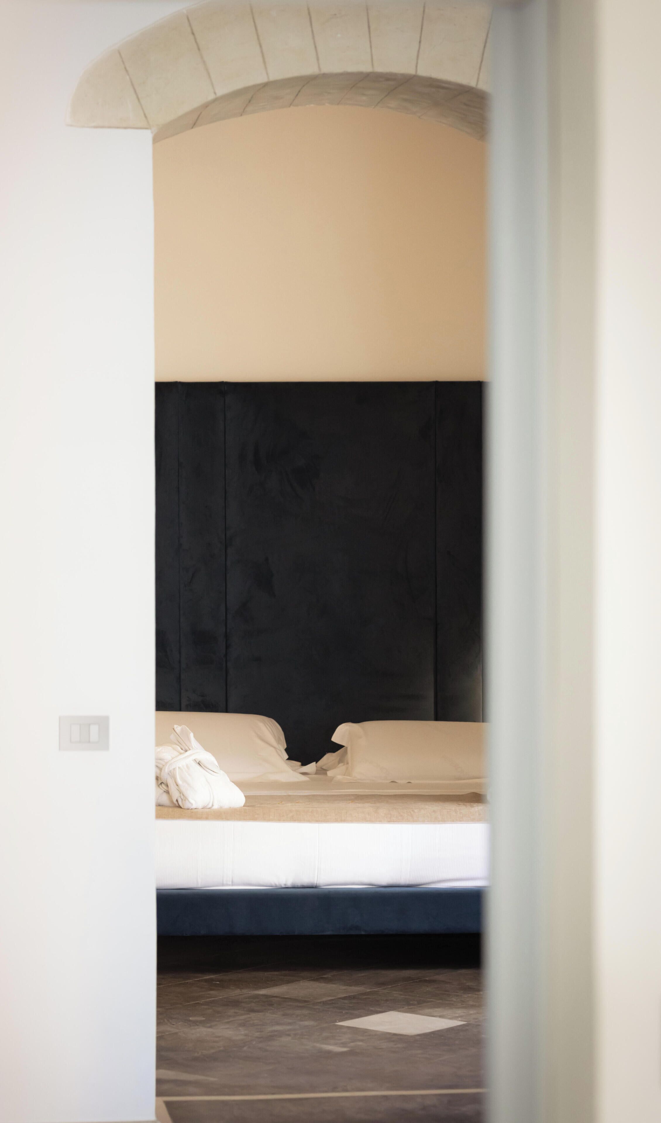 A single bed with a dark headboard, a white pillow, and a beige blanket.