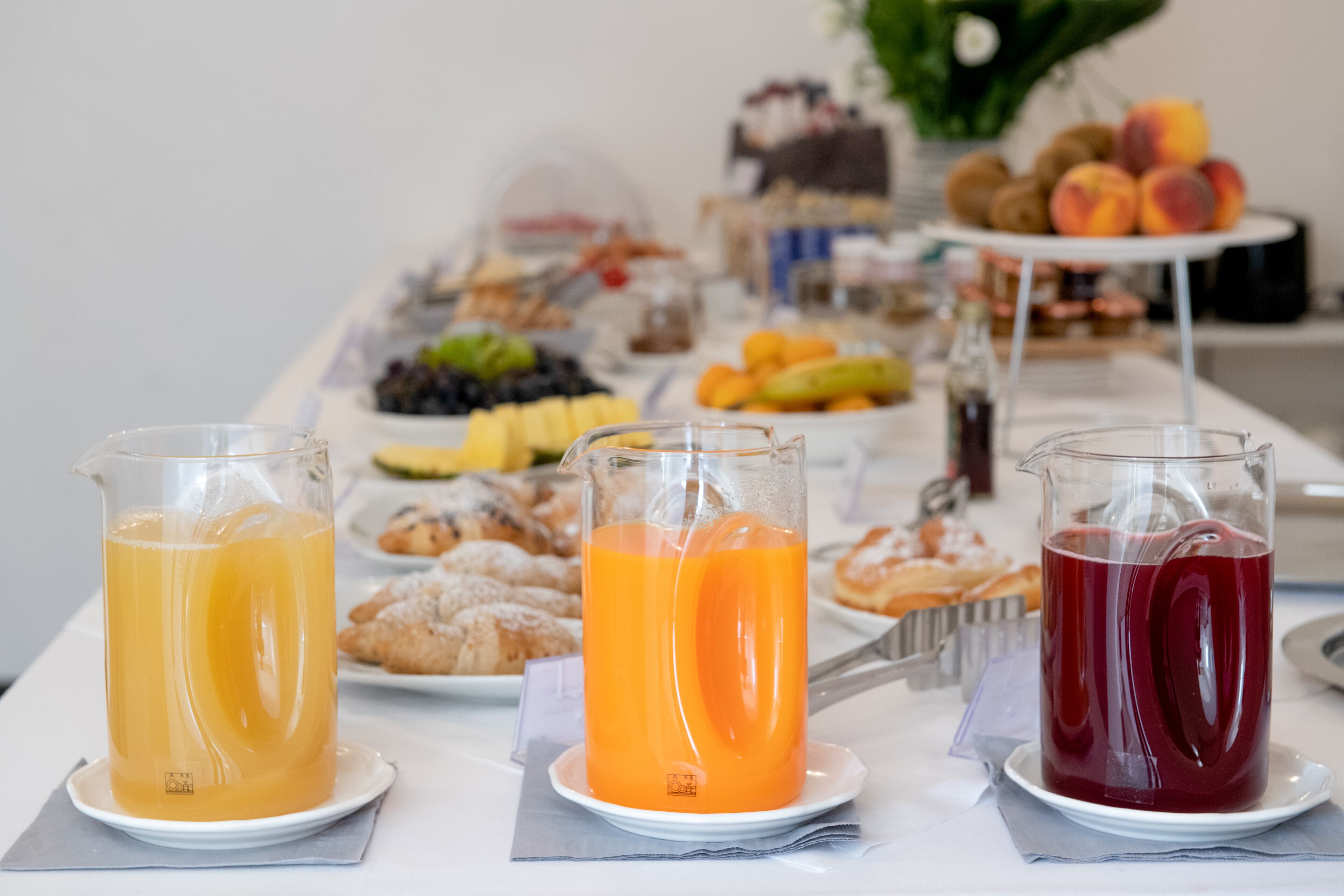 A breakfast buffet with various fruits, pastries, and beverages.