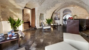 A spacious lobby with a stone archway, a reception desk, and a seating area with a modern sofa and armchairs.