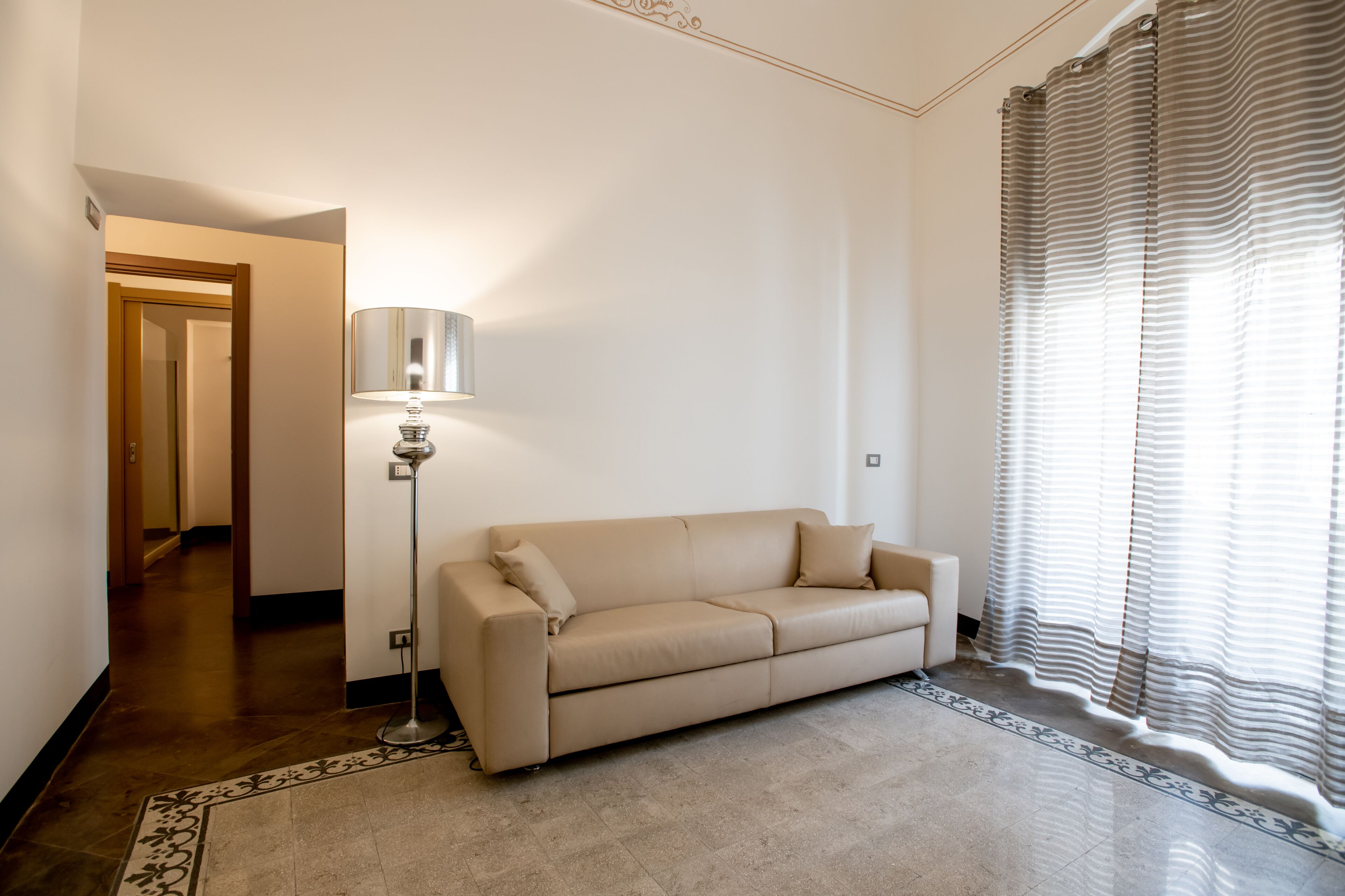 A living room with a beige sofa, a floor lamp, and a patterned rug.