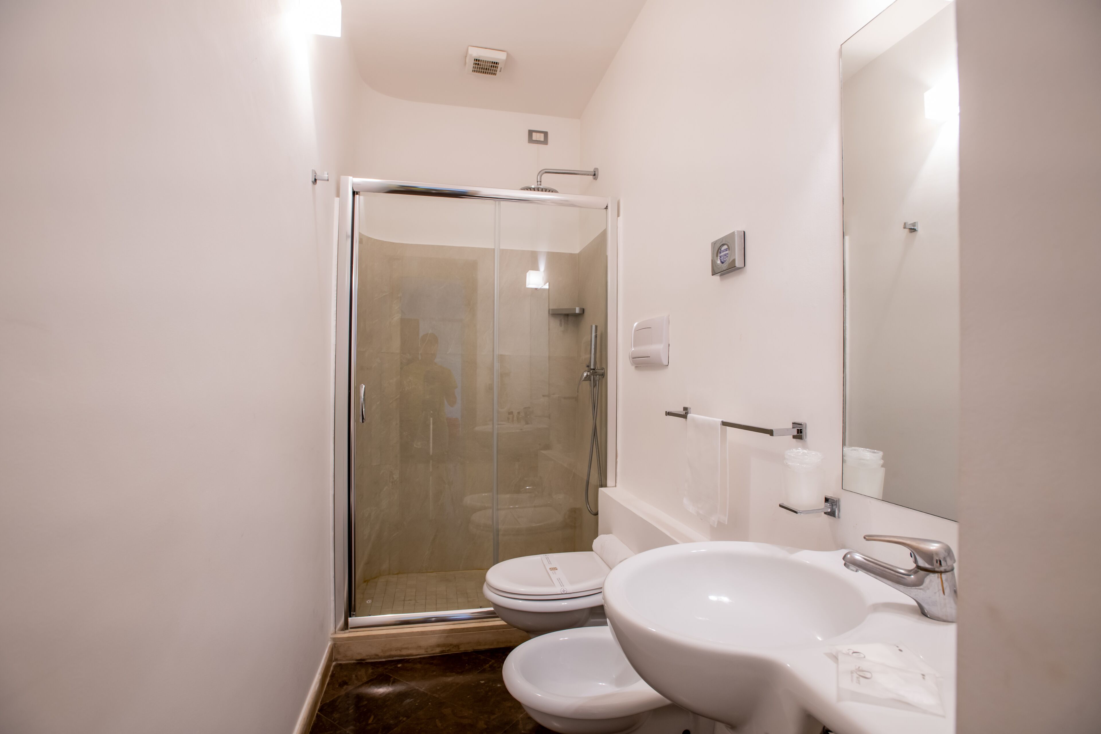 A bathroom with a glass-enclosed shower, a toilet, and a sink with a mirror.