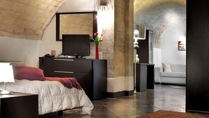A bedroom with a bed, dresser, TV, and a vase with flowers.