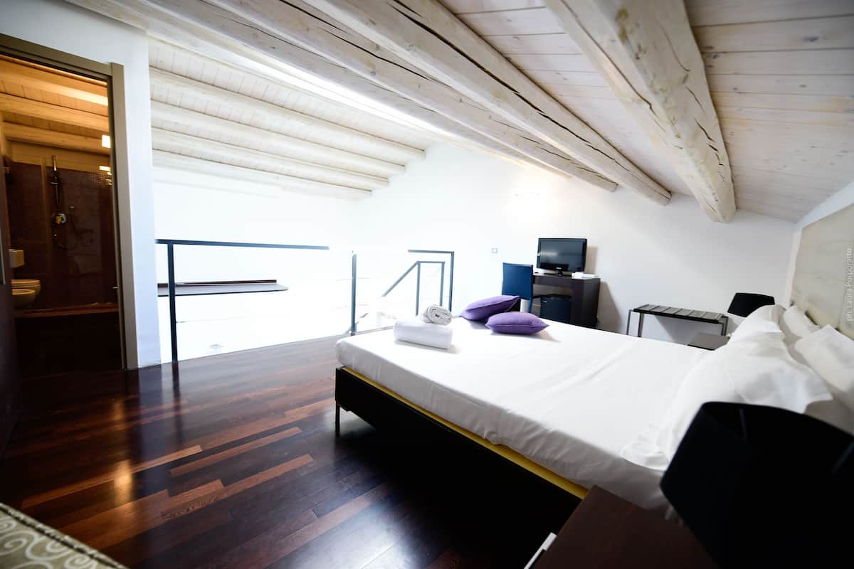 Une chambre à coucher avec un lit, une télévision, un bureau et une fenêtre.