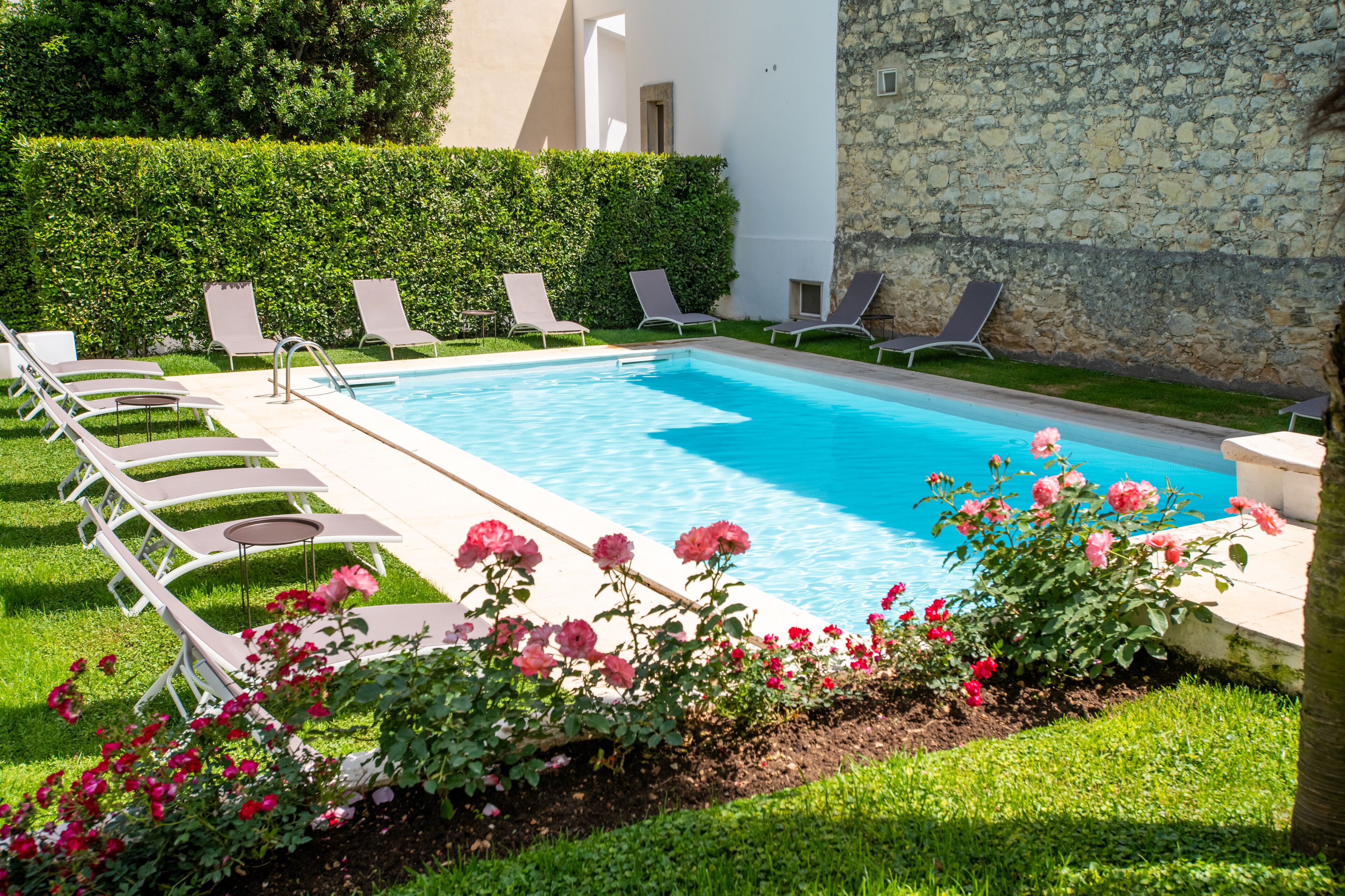 A pool area with lounge chairs and blooming flowers.