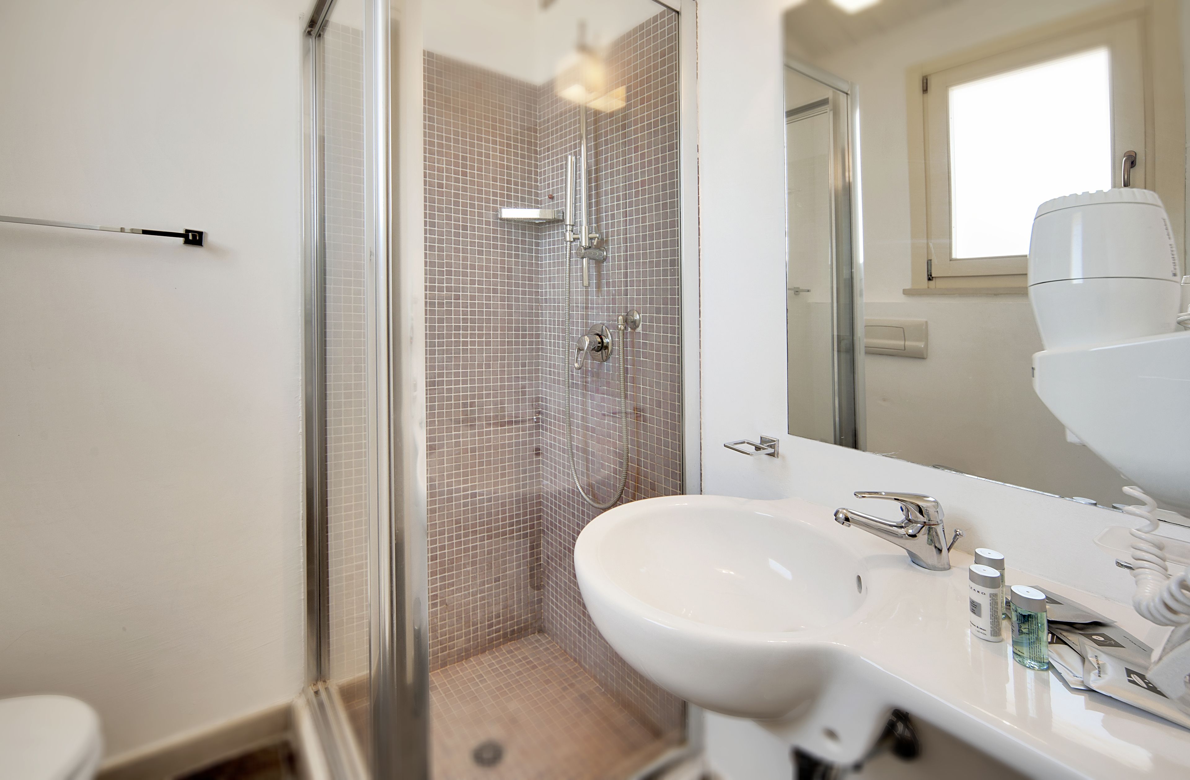 Een moderne badkamer met een douchecabine van glas, een witte wastafel en een grote spiegel.