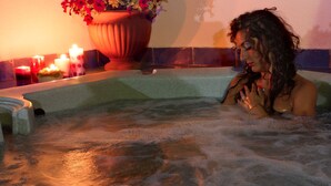 Eine Person in einer Hot Tub mit Kerzen und Blumen im Hintergrund.