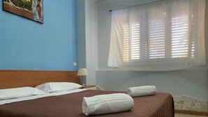 A hotel room with a brown bed, white pillows, and two rolled towels on the bed. - Kassiopea Aparthotel (Giardini Naxos)