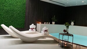 Un área de spa moderna con mostrador de recepción, pared verde y piscina.