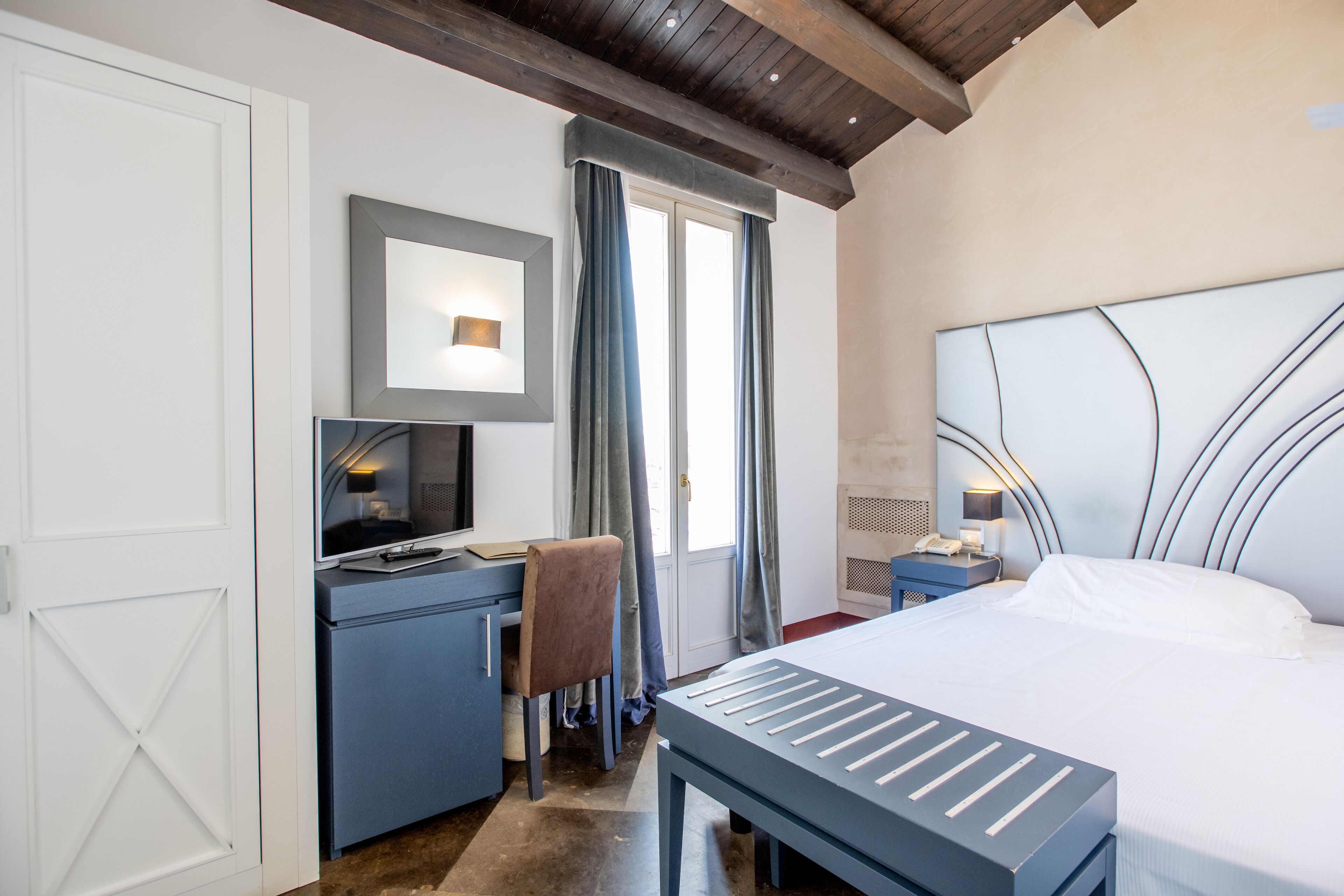 A bedroom with a bed, desk, chair, and nightstands.