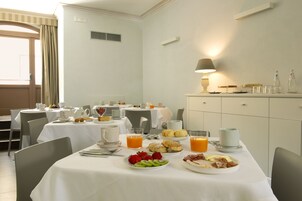 A breakfast setting with tables set for dining, including plates of food, drinks, and cups.