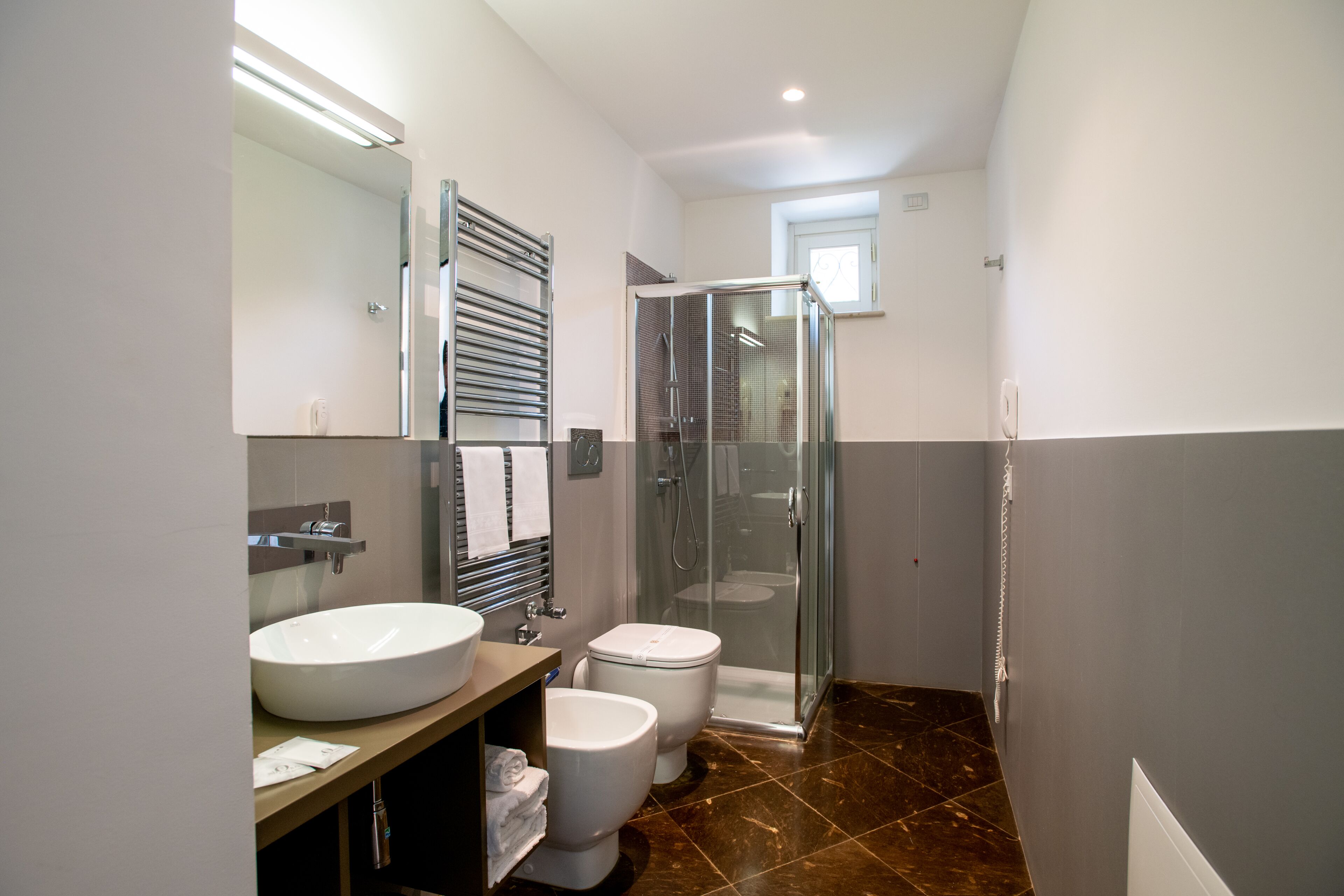 Un bagno moderno con un lavandino spazioso, due servizi igienici, un box doccia in vetro e una doccia a ingresso libero.