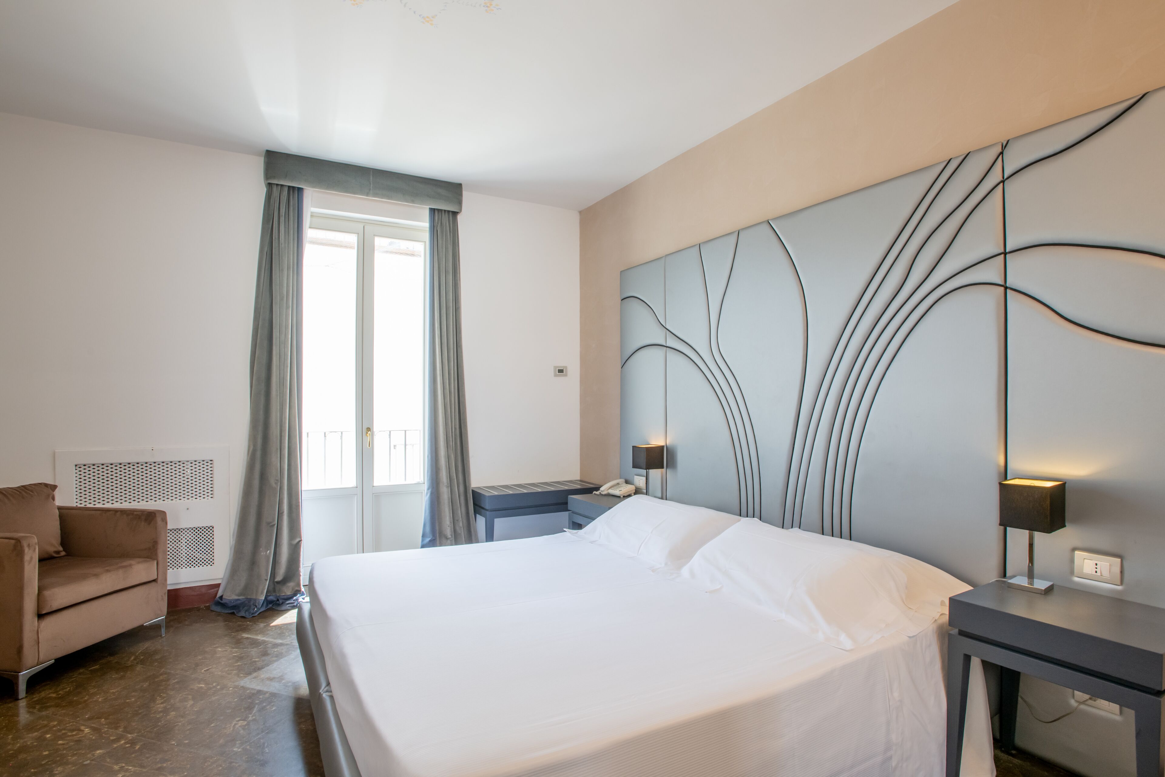 Una camera d'albergo con un letto grande, una scrivania, una sedia e un'opera d'arte appesa al muro.