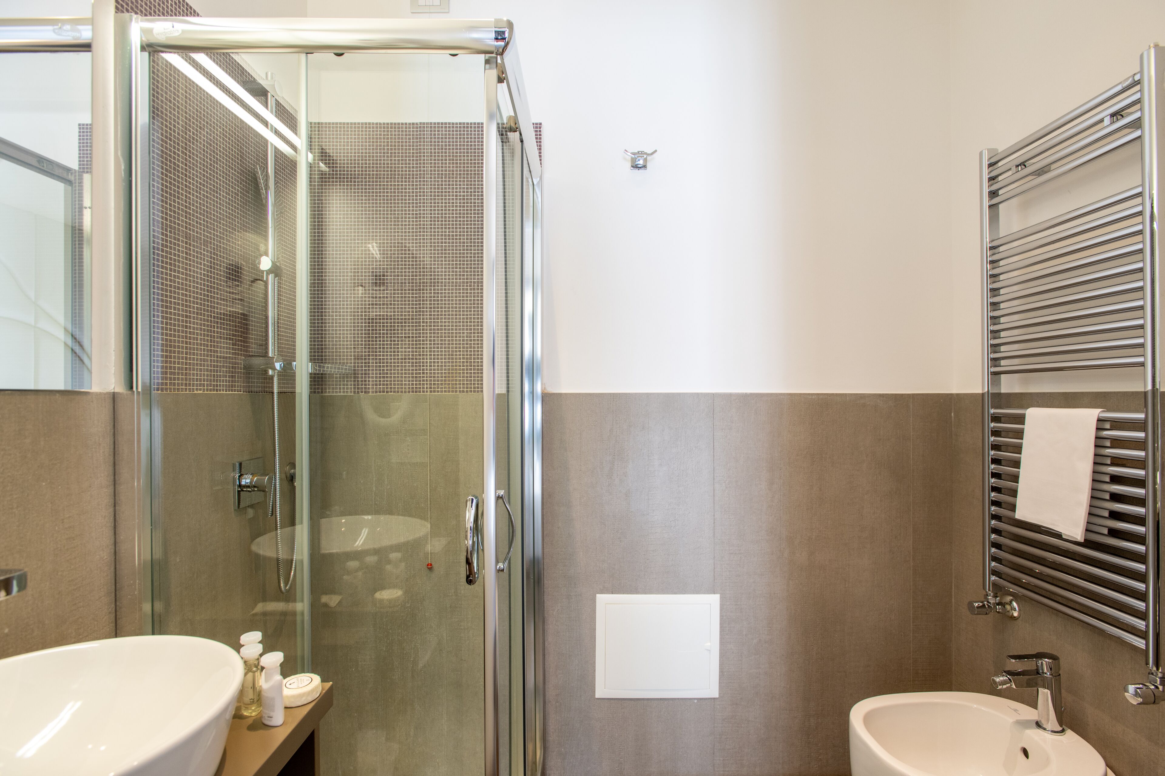 Un baño moderno con cabina de ducha de vidrio, un lavabo y un perchero para toallas.