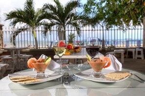 A table with two glasses of a pink drink, a plate of crackers, and a plate of fruit. - Santorini Hotel & Resort (Santa Marta)