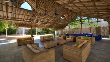 An outdoor seating area with wicker furniture and a thatched roof.