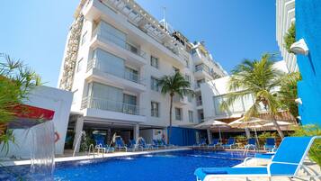 Relax by the rooftop pool surrounded by palm trees and lounge chairs.