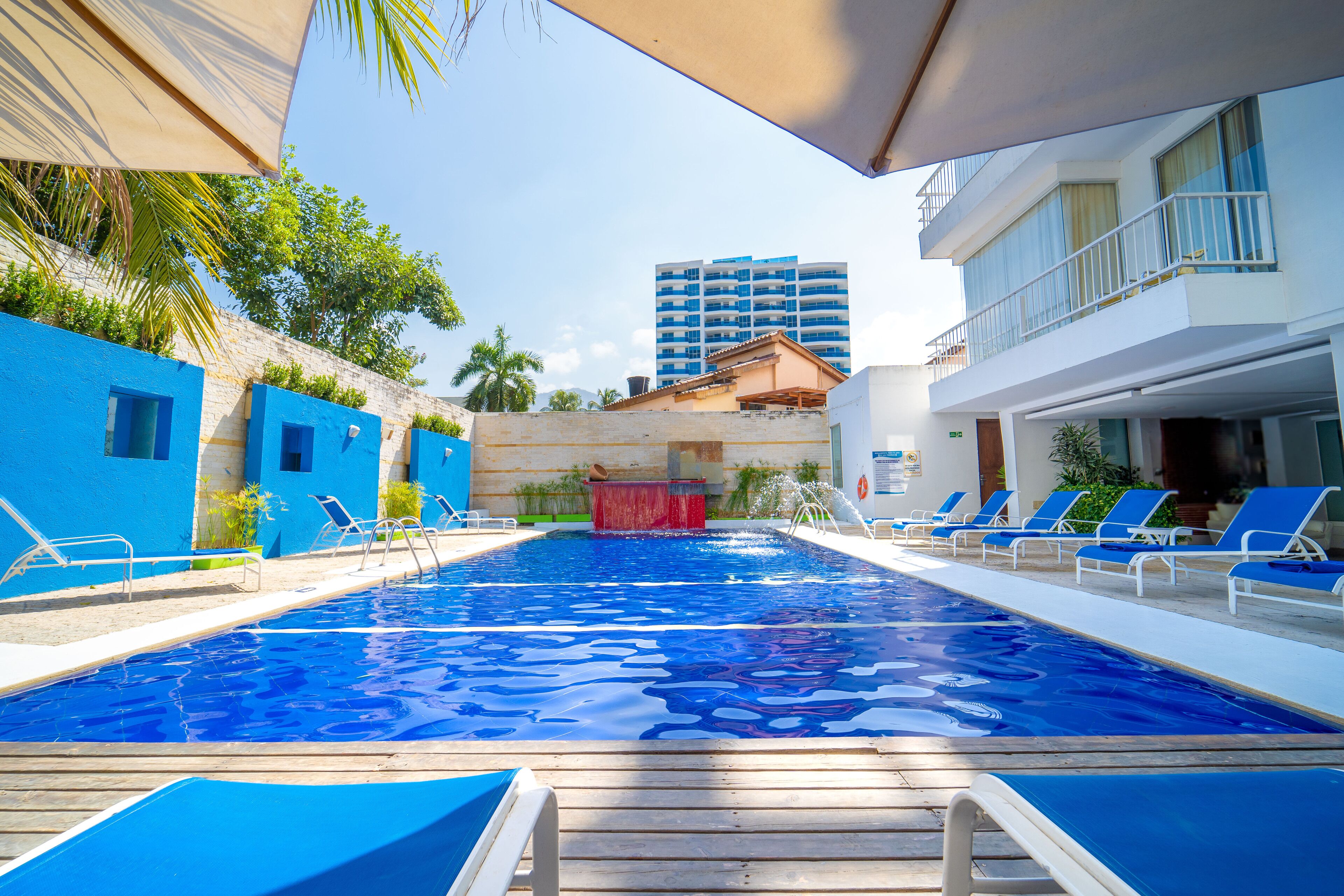 Una piscina con agua azul, rodeada de sillas de descanso y una terraza de madera.