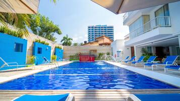 Una piscina con agua azul, rodeada de sillas de descanso y una terraza de madera.
