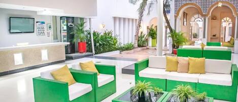A spacious lobby with green and white seating areas, a reception desk, and a modern interior design.