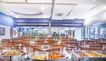 Restaurante com serviço por buffet, diversas estações de comida e cadeiras de madeira.