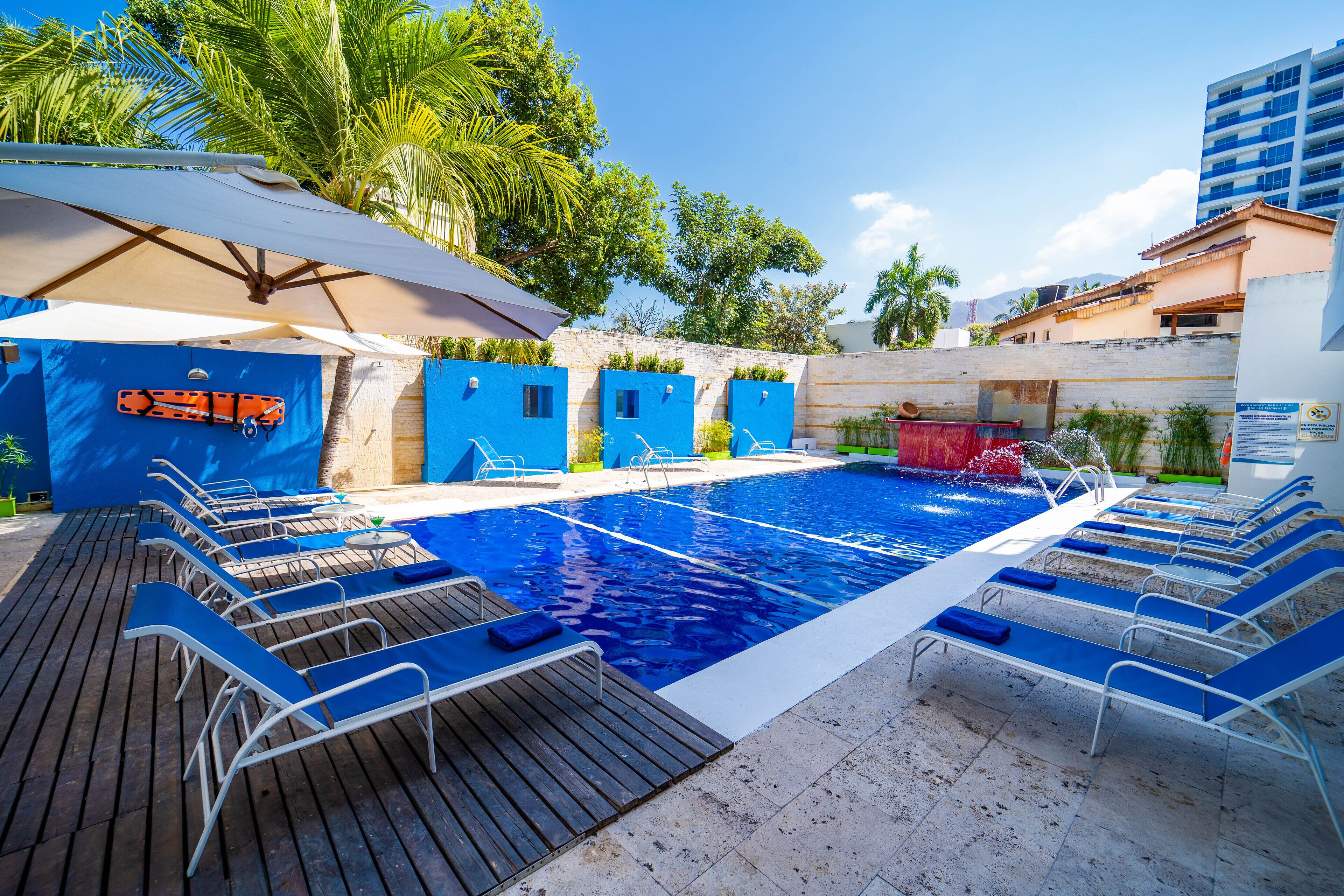 Une piscine avec des chaises longues et un espace abrité équipé de parasols.