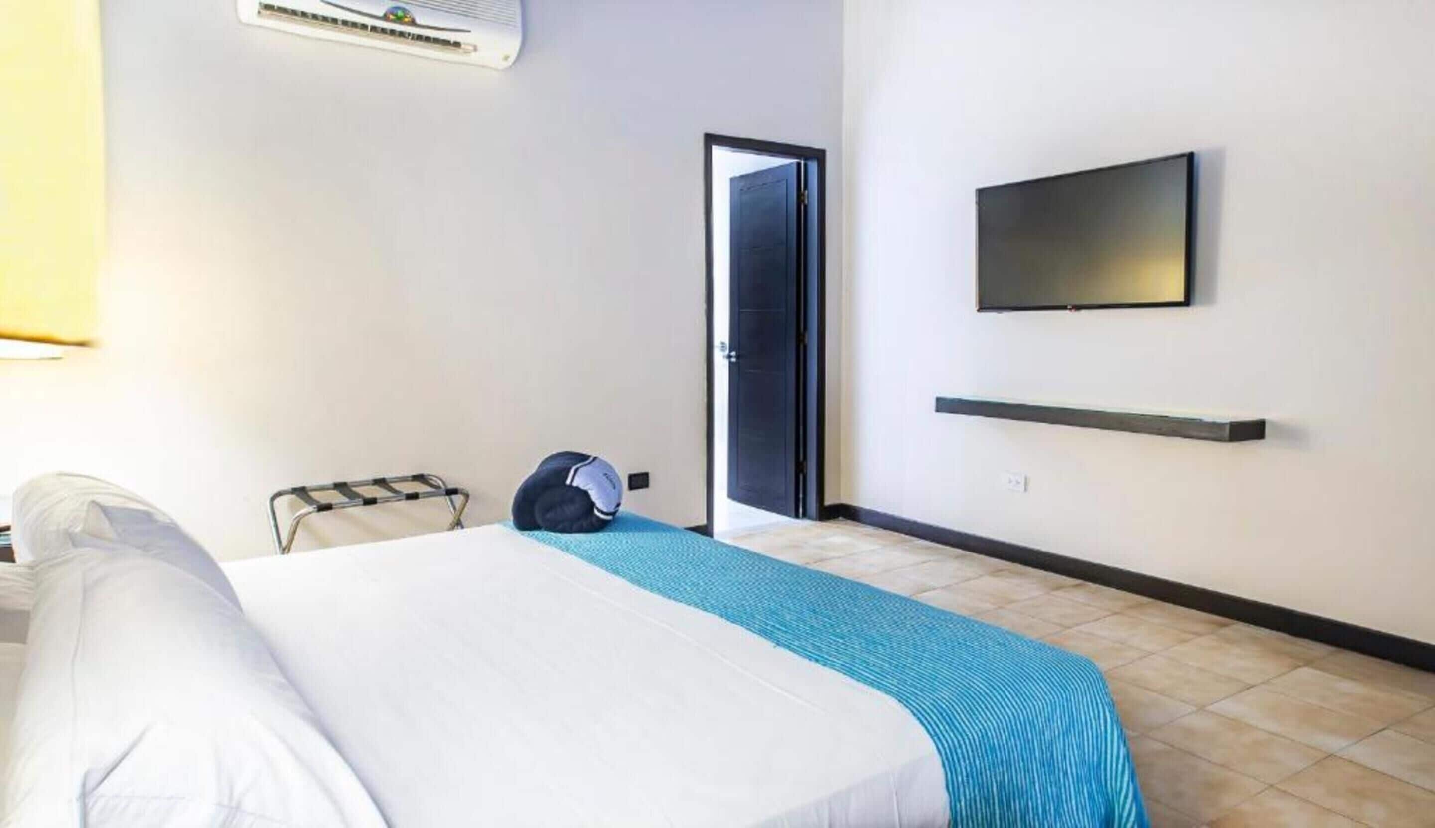 A hotel room with a bed, a TV mounted on the wall, and a door.