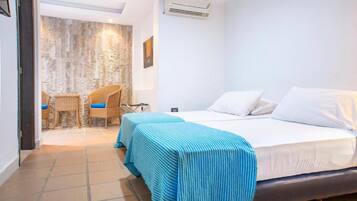 A hotel room with a bed, two chairs, a small table, and a wall with a textured design.