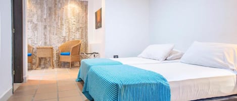 A hotel room with a bed, two chairs, a small table, and a wall with a textured design.