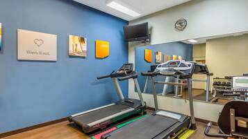 A fitness center with treadmills, a mirrored wall, and motivational posters.
