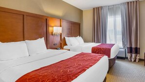A hotel room with two beds, a wooden headboard, a nightstand with a lamp, and a large window with curtains. - Comfort Suites South Point - Huntington (South Point)