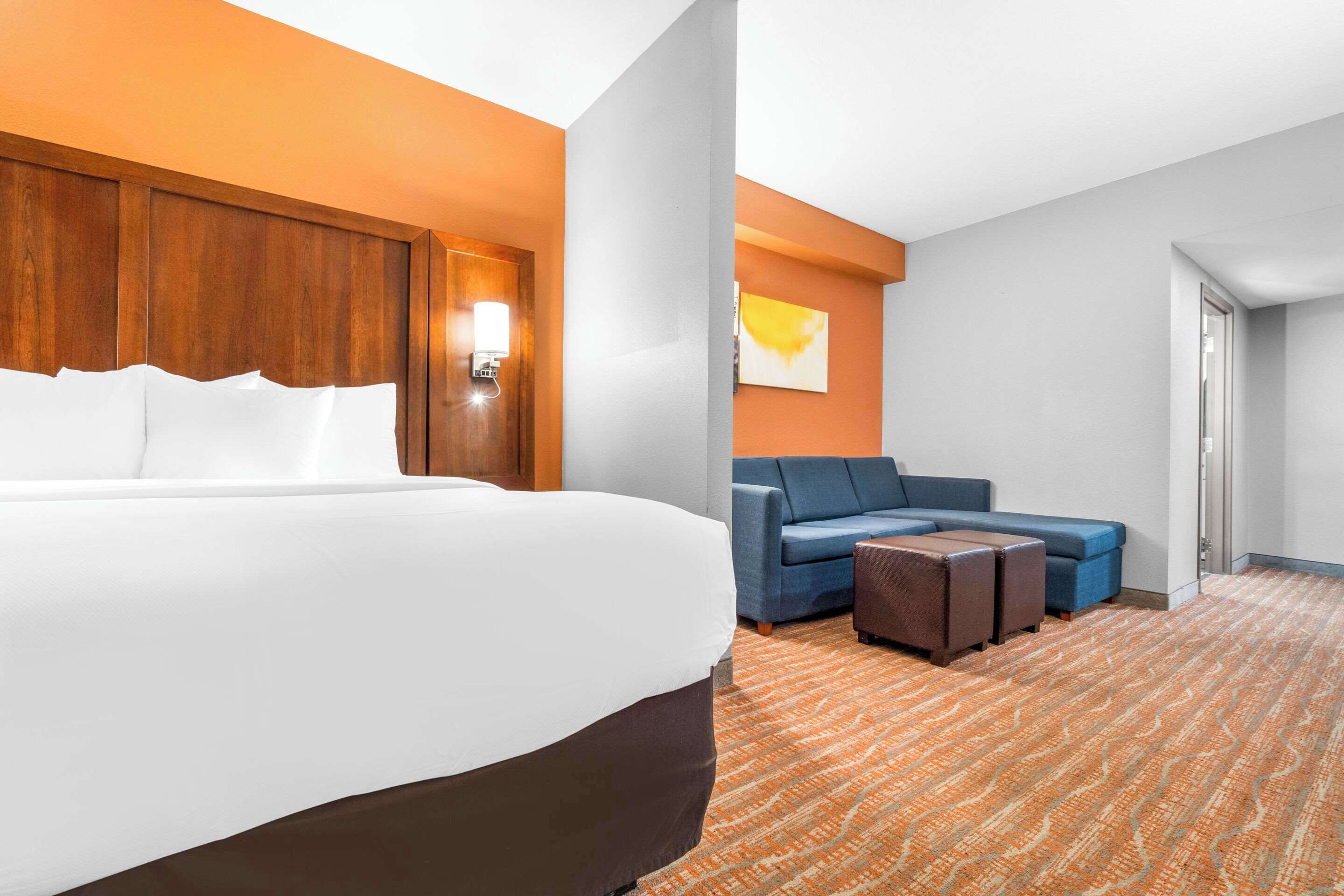 A hotel room with a large bed, a sofa, and a small table.