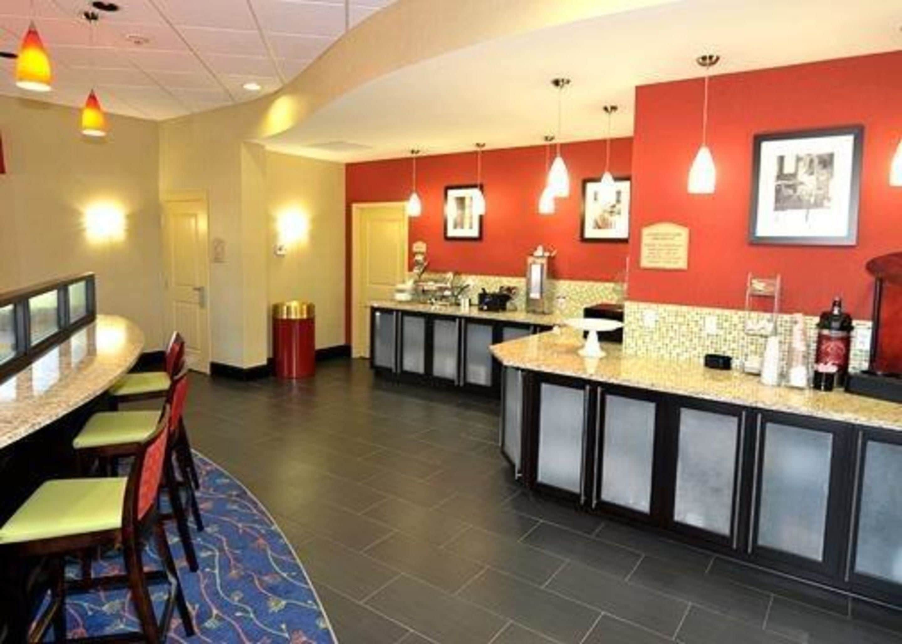 A hotel lobby with a reception desk, seating area, and a counter with a coffee machine.