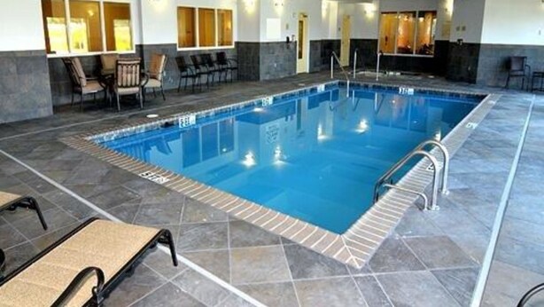 Piscina con cubierta de azulejos, sillas de descanso y zona de bar.