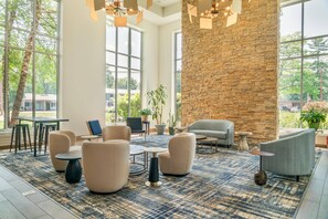 A spacious indoor area with large windows, a stone wall, and modern furniture. - Cambria Hotel Traverse City (Traverse City)