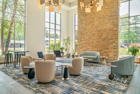 A spacious indoor area with large windows, a stone wall, and modern furniture.