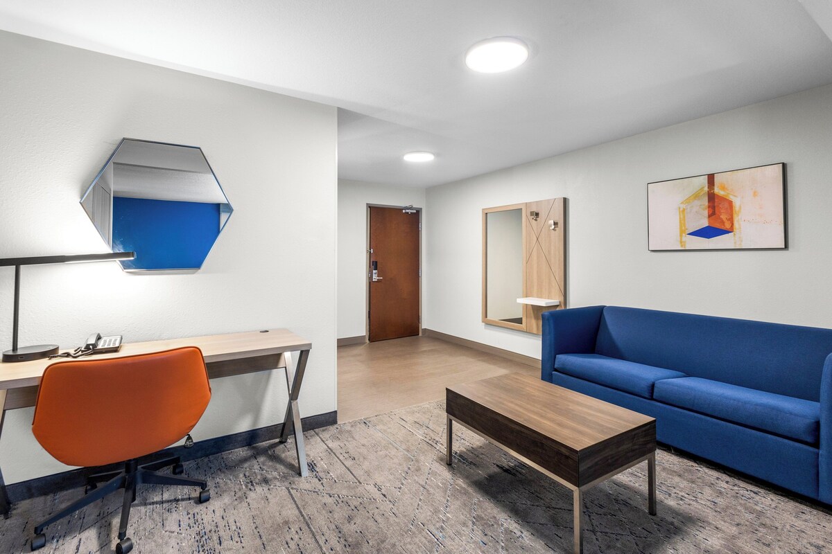 A modern room with a desk, chair, sofa, and a coffee table.