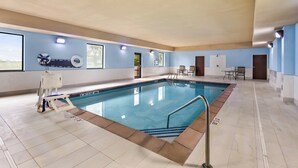 Una piscina interior con agua cristalina, suelo de baldosas y una silla para socorrista.